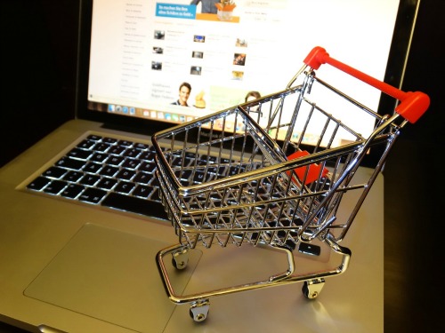 A tiny shopping cart atop the keyboard of a laptop computer