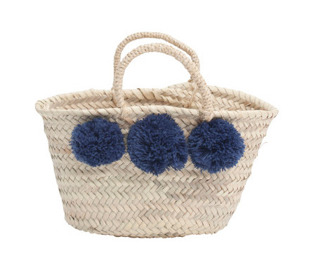 A French-inspired handwoven basket with pom poms