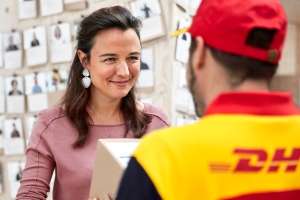 Woman smiling and receiving a parcel form a DHL eCommerce UK delivery driver