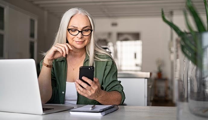 Small business owner reads guide on understanding duties and taxes on her smartphone