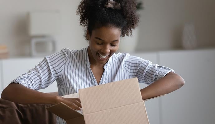 Woman supports small business owner by buying online - happily opens parcel in living room