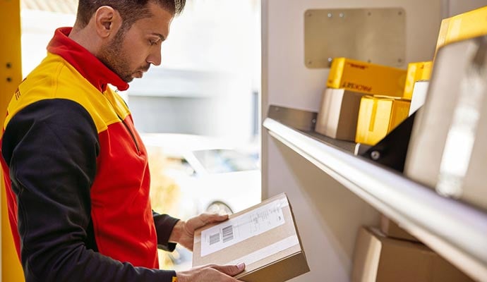 DHL eCommerce UK driver sorts parcels in the back of his van