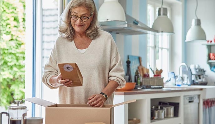 Happy woman open parcel containing coffee which she has bought online