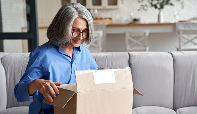 Smiling woman sitting on her sofa opens parcel