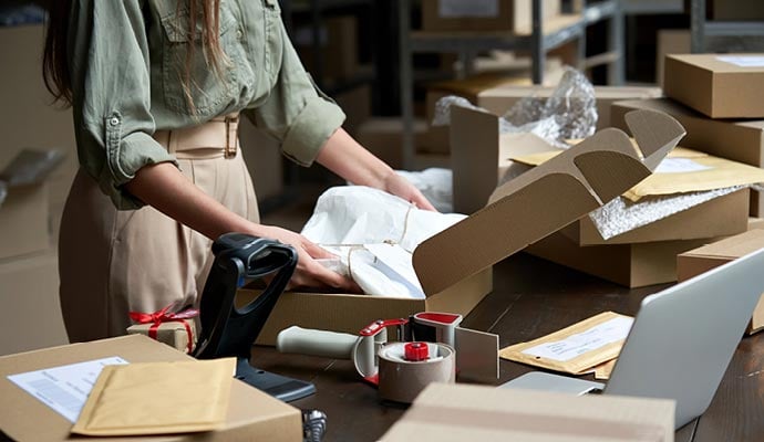 Small business owner in warehouse carefully packages customer's order 