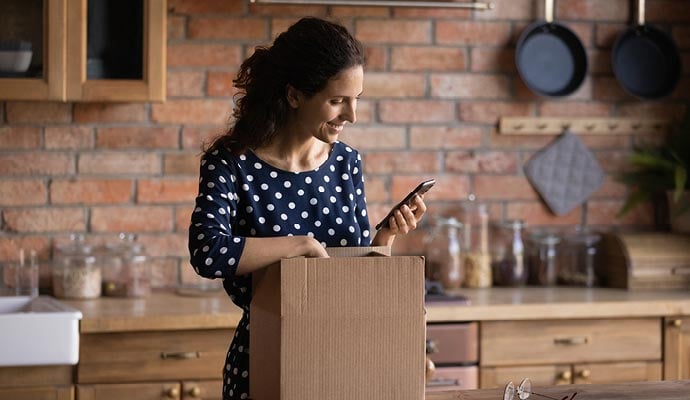 Happy woman opens parcel which has been safely by DHL Parcel UK
